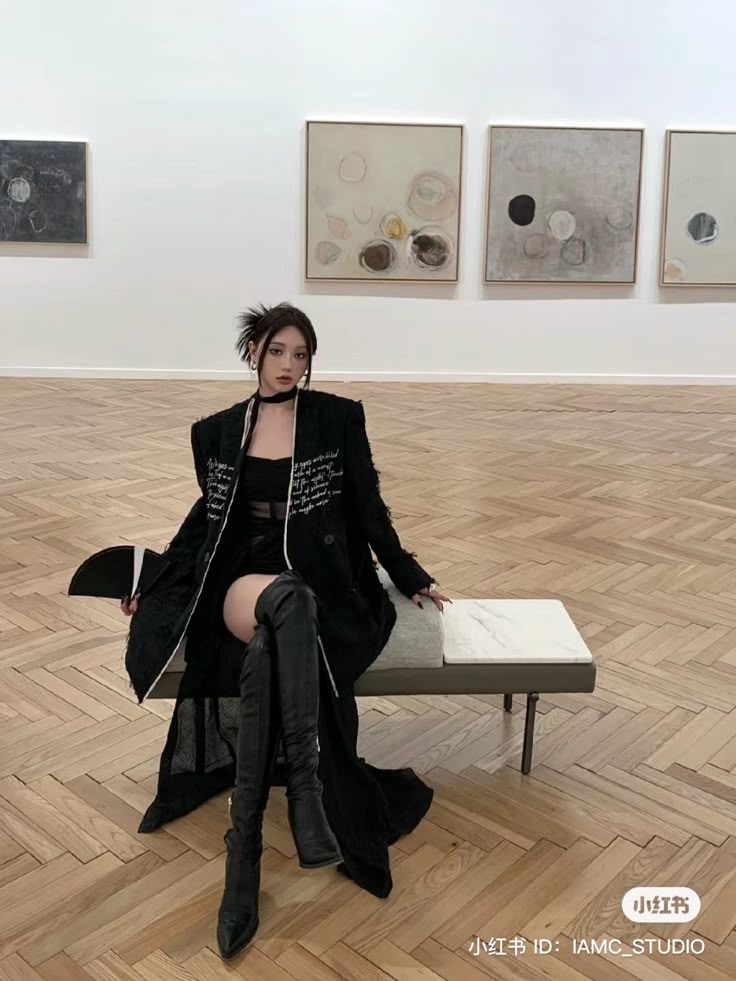 a woman sitting on a bench in front of a wall of paintings